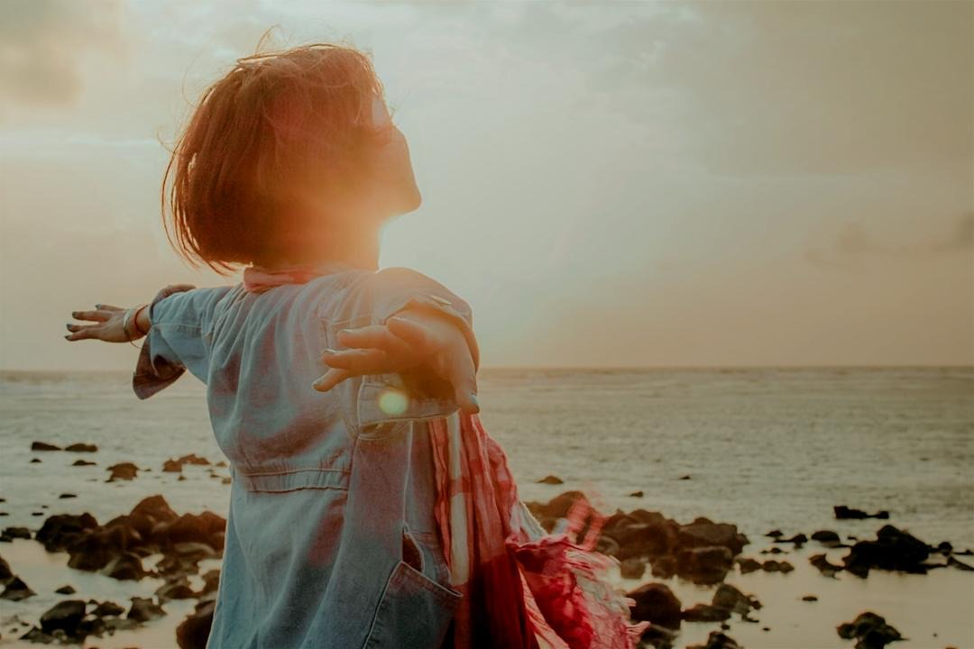 Person standing by the sea with arms outstretched